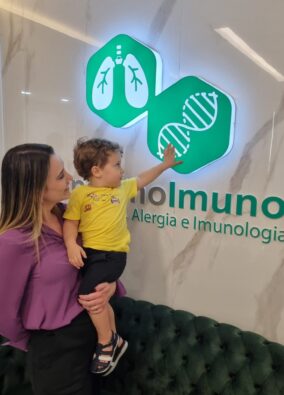 Médica Dra Larissa Cau Carlet com paciente pediátrico no logo da Clínica PneumoImuno